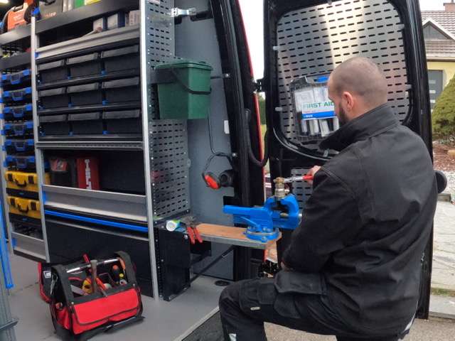spécialiste chauffagiste de N'Rgie SAV se préparant à intervenir dans un logement en choisissant ses outils professionnels dans sa camionnette